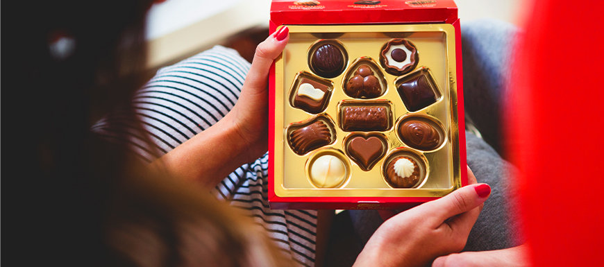 Couple holding box of holiday chocolates.